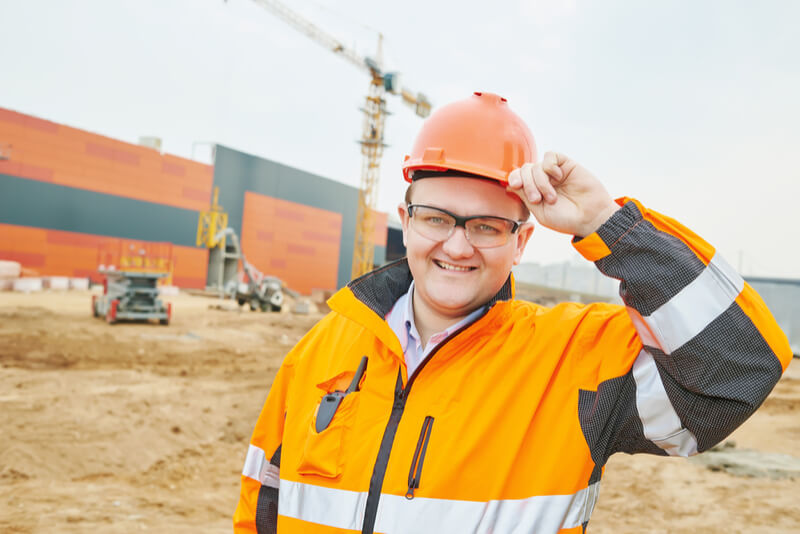 work man wearing orange hi visibility workwear tipping his helmet